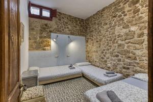Habitación con 2 camas y pared de piedra. en Casa Blava en Orriols