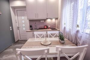 cocina con armarios blancos, mesa y 2 sillas en Dream Luxury Home, en Xylokastro