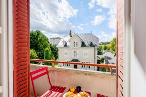 una silla roja sentada en un balcón con vistas en Le Nid d'Ernest, en Voiron