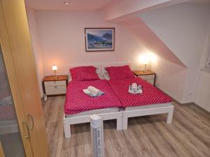 a bedroom with a bed with red sheets and two lamps at Capital Apartments in Düren - Eifel