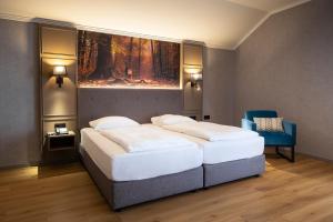 a bedroom with two beds and a blue chair at ACHAT Hotel Waldkirchen in Waldkirchen
