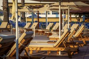 een rij ligstoelen en parasols op een patio bij Hotel Kanali in Kanali