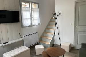 a living room with a staircase and a table at Le Petit Cellier in Coulommes-la-Montagne