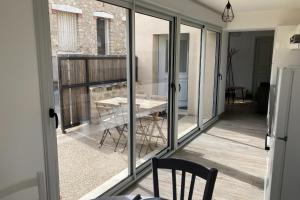 een kamer met glazen deuren en een tafel op een balkon bij Le Petit Cellier 