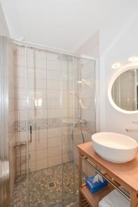 een badkamer met een wastafel en een glazen douche bij Le Petit Cellier 