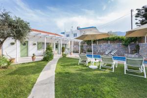 a house with a yard with chairs and an umbrella at Pelagias Villa in Kavros