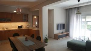 a living room with a table and a kitchen at Feather Apartments-Nea Moudania Halkidiki in Nea Moudania
