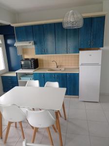 a kitchen with blue cabinets and a white table and chairs at OLIVE&VIEW in Nea Moudania +11 photos
