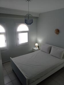 a bedroom with a white bed and two windows at OLIVE&VIEW in Nea Moudania