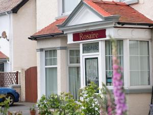 dom z różowym znakiem pielęgniarskim w oknie w obiekcie Rosaire Guest House w mieście Llandudno