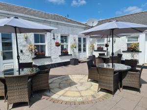 eine Terrasse mit Tischen, Stühlen und Sonnenschirmen in der Unterkunft Dunderry Lodge Self Catering Family Lodges in Navan