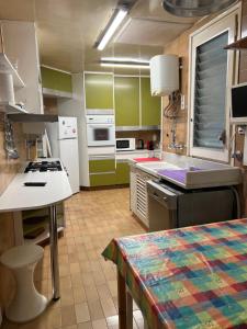 a kitchen with green and white cabinets and a table at Gran piso Terrassa centro rambla 5 habitaciones in Terrassa