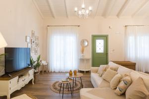 a living room with a white couch and a tv at Pelagias Villa in Kavros