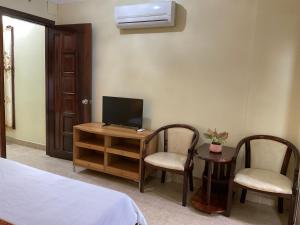 1 dormitorio con 1 cama, TV y 2 sillas en Khách sạn Minh Châu - Hòa Hưng, en Ho Chi Minh