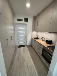 uma cozinha com armários brancos e piso em madeira em Bez7 Apartman em Budapeste