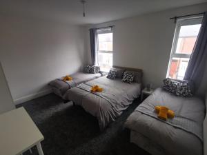 una camera con tre letti con archi arancioni di Sutherland Place - Near Derby City Center a Derby