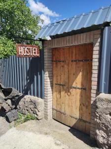 a wooden garage with a wooden door and a sign at ATI MTA - Eco Hostel in Borjomi