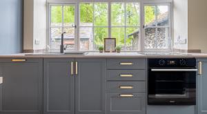 cocina con armarios grises, fregadero y ventana en Home Farmhouse, en Rusland