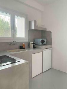 a white kitchen with a sink and a microwave at 31 Seafront Apartment in Kampos Paros +21 photos
