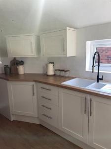 a kitchen with white cabinets and a sink at Churchview Apartments in Seaham