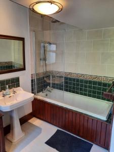 a bathroom with a sink and a tub and a mirror at Jacobite Rose in Inverness