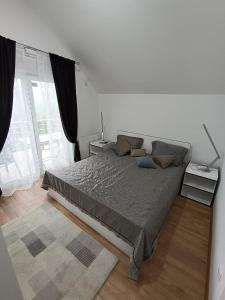 ein Schlafzimmer mit einem großen Bett und einem großen Fenster in der Unterkunft Nahorevska vikendica in Sarajevo