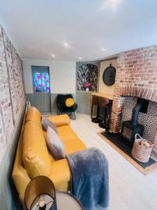 ein Wohnzimmer mit einem gelben Sofa und einem gemauerten Kamin in der Unterkunft Little Pilgrims Retreat in St Dunstans, Canterbury in Kent