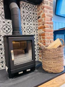 a wood stove sitting next to a wicker basket at Little Pilgrims Retreat in St Dunstans, Canterbury in Kent
