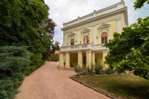 a large yellow house with a brick driveway at Puchner Kastélyszálló Prémium in Bikal