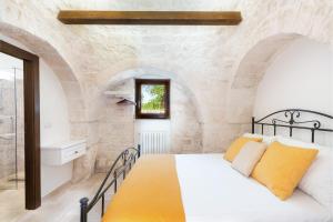 a bedroom with a bed in a stone wall at Trullo Alba in Martina Franca
