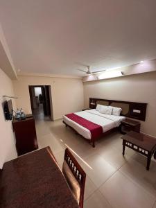 ein Schlafzimmer mit einem Bett, einem Sofa und einem Tisch in der Unterkunft Pagoda Heritage Inn in Alappuzha