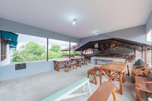 a restaurant with wooden tables and chairs and windows at Urbanview Hotel Tropical Ketapang by RedDoorz in Karawang