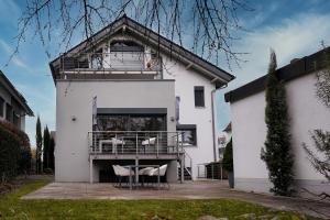 a white house with a balcony and two chairs at Design Apartment in Eppelheim in Eppelheim