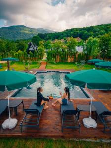 a couple sitting on a deck next to a swimming pool at Palm Bungalov Hotel in Kartepe