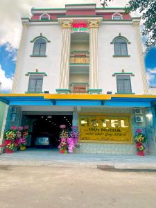 a store front of a white building with flowers in front at Khách Sạn Hội Nghĩa Bình Dương in Hoi Nghia