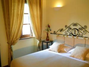 a bedroom with a bed with white sheets and a window at Tenuta Calabiana in Diano dʼAlba