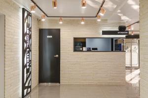 a lobby with a black door and a brick wall at Eumseong Hotel Luem in Eumseong