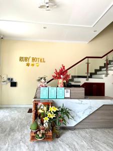 RUBY HOTEL في Tây Ninh: لوبي مع لافتة الفندق وورود على طاولة