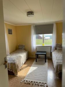 a room with two beds and a window and a rug at Patterdale farm holiday apartments in Gamleby