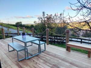 uma mesa azul e um banco num deque de madeira em Secluded, private rural retreat mins from Warkworth -"Avondale" Minihouse em Warkworth