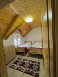 two beds in a room with wooden ceilings at Guesthouse Gezim Selimaj in Valbonë