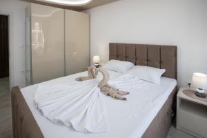 een slaapkamer met een groot bed met witte lakens bij Апартамент за гости Ивви-2 in Boergas