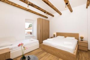 two beds in a bedroom with white walls and wooden floors at Apartments Maginja in Veli Lošinj