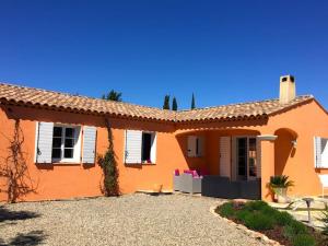 duży pomarańczowy dom z białymi oknami i podjazdem w obiekcie villa des chênes w mieście Flayosc