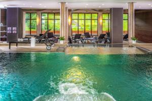 ザンクト・ゲオルゲン・オプ・ムーラウにあるRelax Resort Hotel Kreischbergの椅子とテーブル付きの客室の中央にプールがあります。
