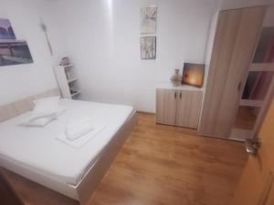 1 dormitorio con cama blanca y suelo de madera en Apartament Ciresica, en Constanţa