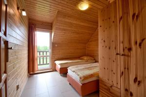two beds in a wooden room with a window at Domki Biały Łabędź in Jarosławiec