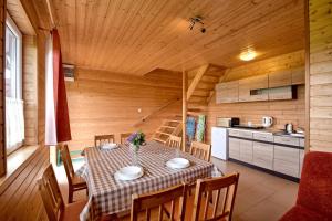 a dining room with a table and a kitchen at Domki Biały Łabędź in Jarosławiec