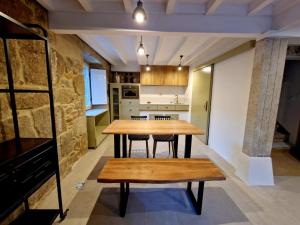 a kitchen and dining room with a wooden table and bench at PEREGRINA in Villanueva de Arosa