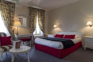 ein Schlafzimmer mit einem großen Bett mit roten Kissen in der Unterkunft Hôtel de L'univers in Arras